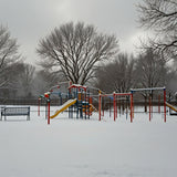 A park with snow-covered playground equipment and trees (1)