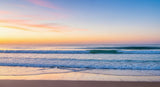 Beautiful twilight scene with soft waves meeting the shore under a colorful sky, evoking peace and tranquility.