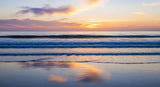 Beautiful twilight scene with soft waves meeting the shore under a colorful sky, evoking peace and tranquility.